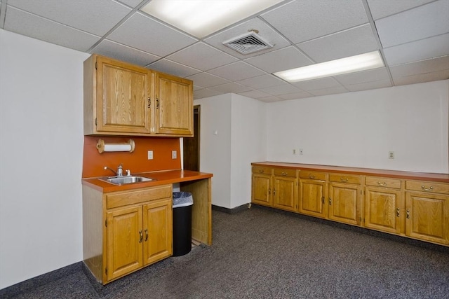 kitchen featuring a drop ceiling, visible vents, baseboards, and a sink