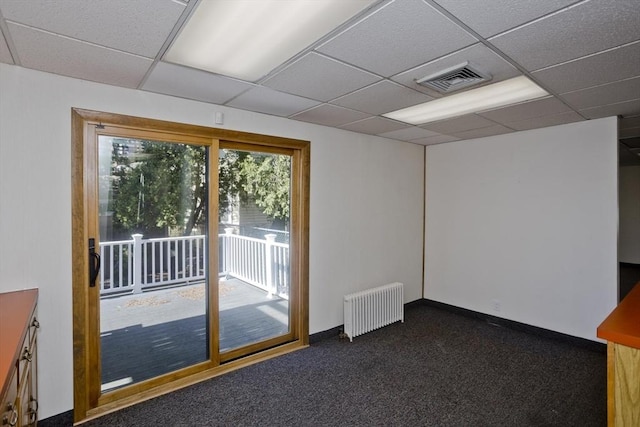 empty room with a paneled ceiling, radiator, visible vents, and carpet