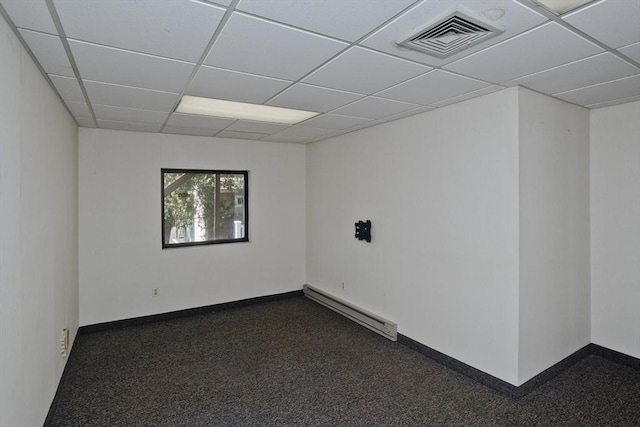 empty room with a paneled ceiling, visible vents, baseboards, dark colored carpet, and a baseboard radiator