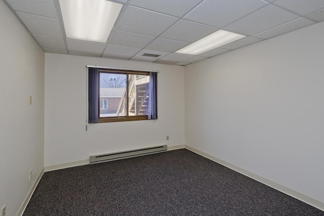 unfurnished room featuring a baseboard heating unit, visible vents, carpet floors, a paneled ceiling, and baseboards