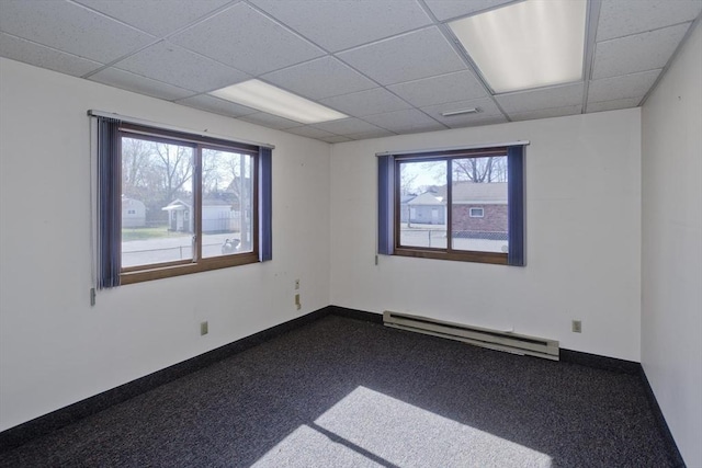 unfurnished room with a paneled ceiling, baseboards, baseboard heating, and plenty of natural light