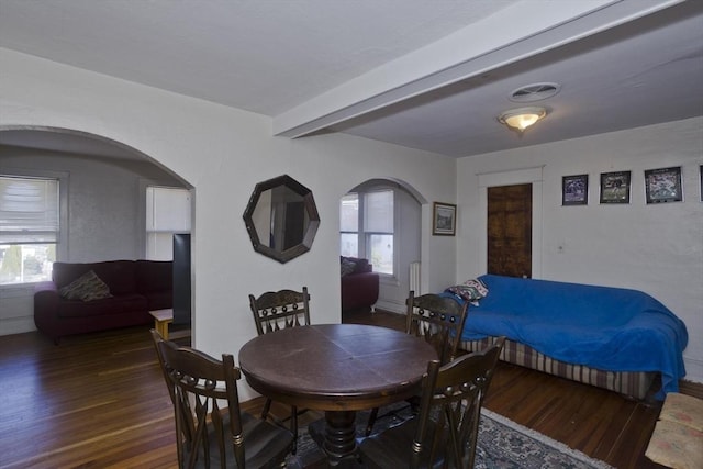 dining space featuring arched walkways, visible vents, beam ceiling, and wood finished floors