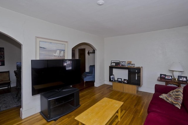 living area featuring arched walkways and wood finished floors