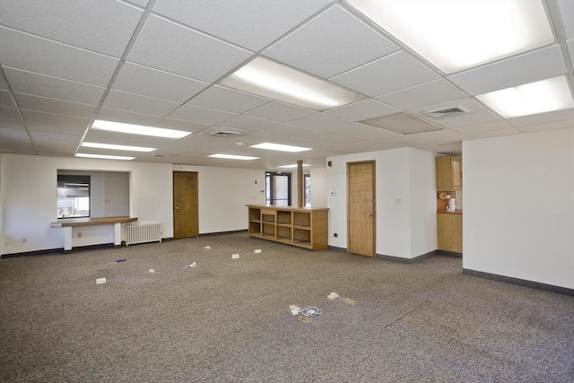 unfurnished room featuring a drop ceiling, baseboards, visible vents, and radiator heating unit