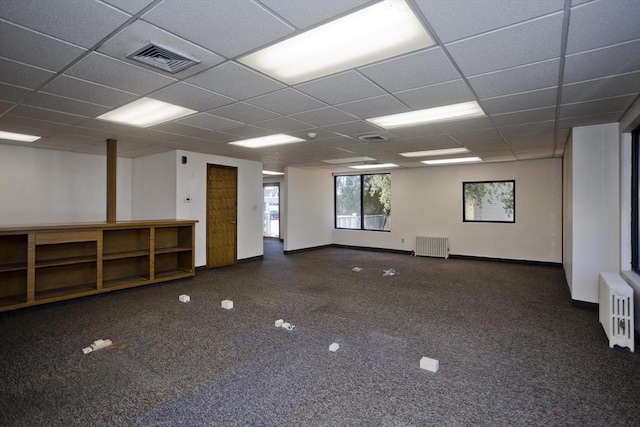 carpeted spare room featuring radiator, a drop ceiling, and visible vents