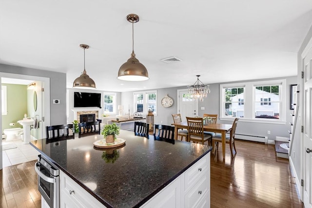 30 Millard Ave, Lynn, MA 01904 - kitchen with baseboard heating, stainless steel oven, dark wood-style flooring, white cabinetry, and a glass covered fireplace