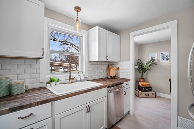 kitchen with sink, dishwasher, hanging light fixtures, white cabinets, and wood counters