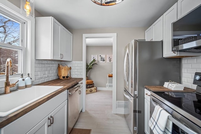 kitchen featuring wood counters, sink, white cabinetry, and stainless steel appliances