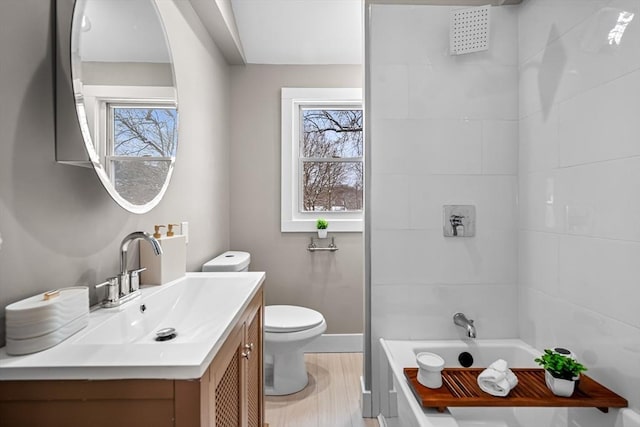 full bathroom featuring vanity, wood-type flooring, tiled shower / bath, and toilet