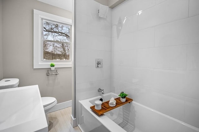 full bathroom featuring hardwood / wood-style flooring, tiled shower / bath, toilet, and sink