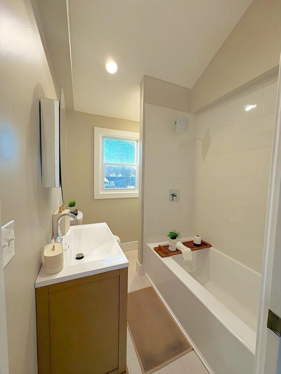 bathroom featuring lofted ceiling, vanity, and a bath