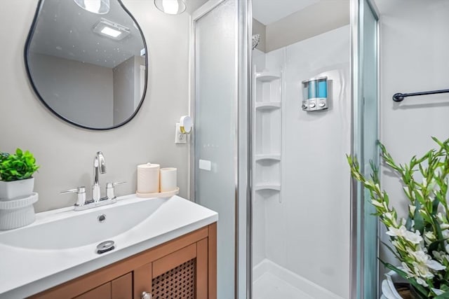 bathroom featuring a shower with door and vanity