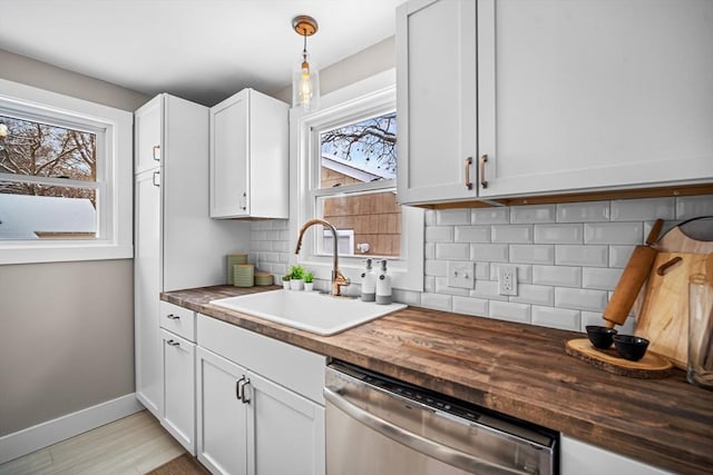 kitchen with wood counters, hanging light fixtures, stainless steel dishwasher, and white cabinets