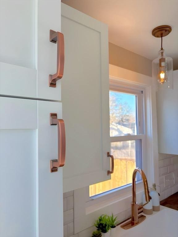 interior space with white cabinetry, hanging light fixtures, and sink