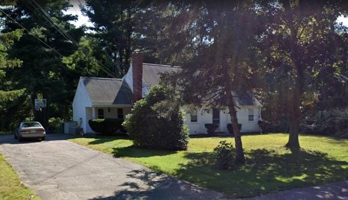 view of front of property with a chimney, a front yard, and driveway