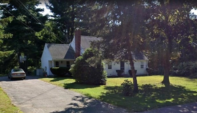 view of front of property with a chimney, a front yard, and driveway