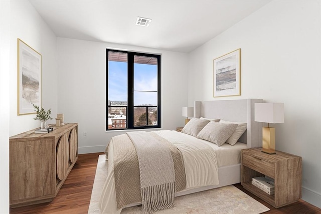 bedroom with baseboards, visible vents, and wood finished floors