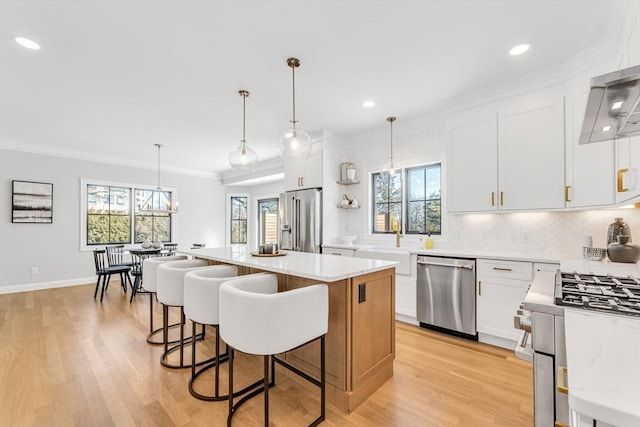 kitchen featuring white cabinetry, light hardwood / wood-style flooring, appliances with stainless steel finishes, a kitchen island, and pendant lighting