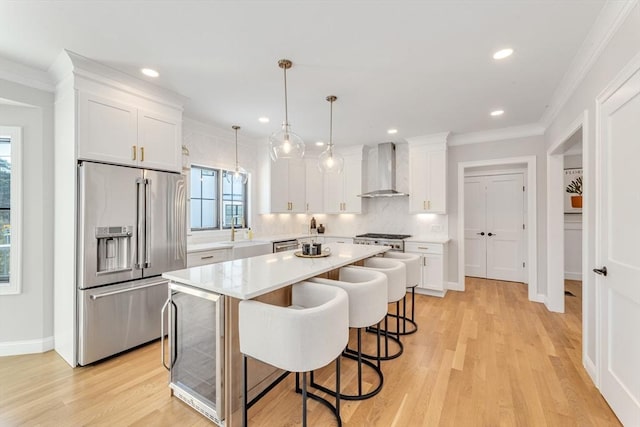 kitchen featuring wall chimney exhaust hood, white cabinetry, high end refrigerator, a center island, and pendant lighting