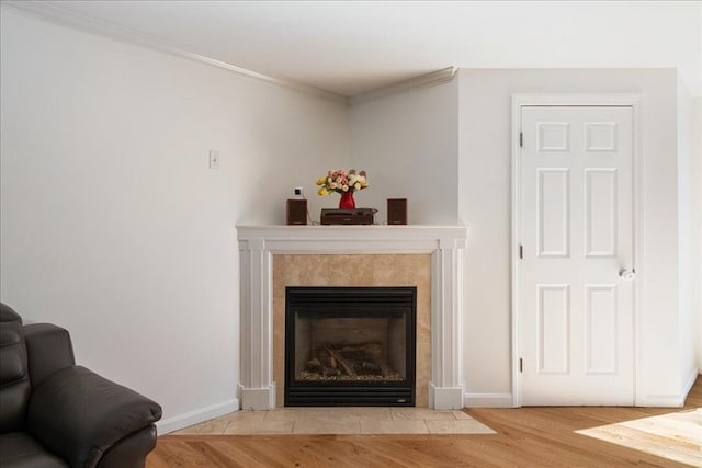 interior details with crown molding, baseboards, a tile fireplace, and wood finished floors