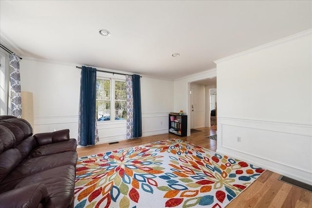 living area featuring crown molding, recessed lighting, wood finished floors, and a decorative wall