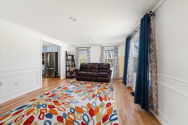 living room with light wood-style floors and ornamental molding