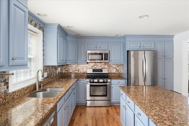 kitchen featuring backsplash, light wood-type flooring, a sink, dark stone countertops, and stainless steel appliances