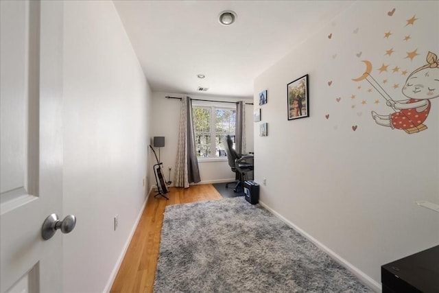 office space with baseboards, light wood finished floors, and visible vents