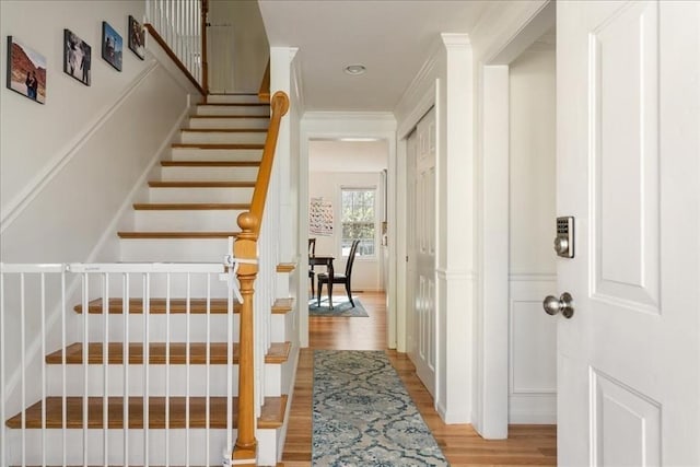 staircase with crown molding and wood finished floors