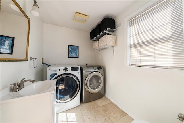 clothes washing area with washer and dryer, light tile patterned flooring, laundry area, a sink, and baseboards