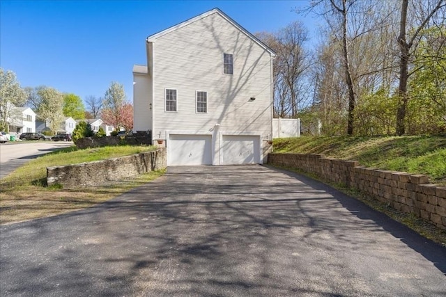 view of side of home featuring an attached garage and driveway