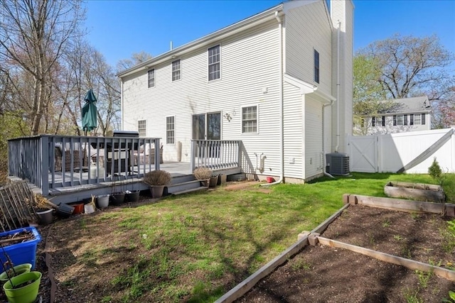 back of property with central AC, a deck, a vegetable garden, a chimney, and a lawn