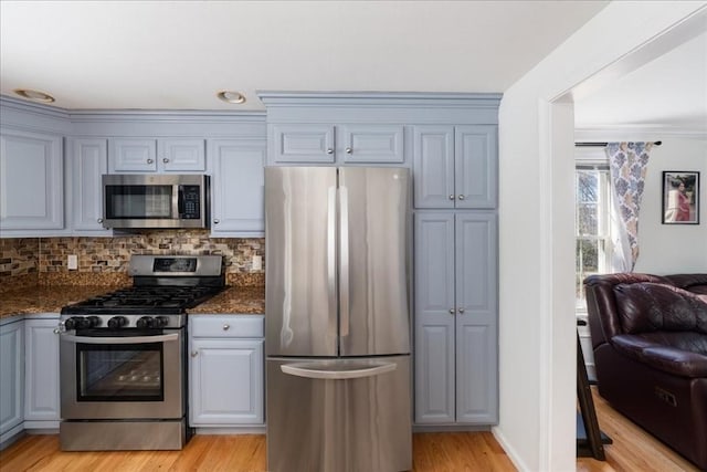 kitchen with gray cabinets, tasteful backsplash, light wood finished floors, open floor plan, and stainless steel appliances