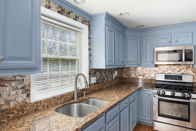 kitchen with a sink, appliances with stainless steel finishes, decorative backsplash, and blue cabinetry