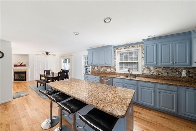 kitchen with a sink, decorative backsplash, stainless steel dishwasher, and blue cabinetry