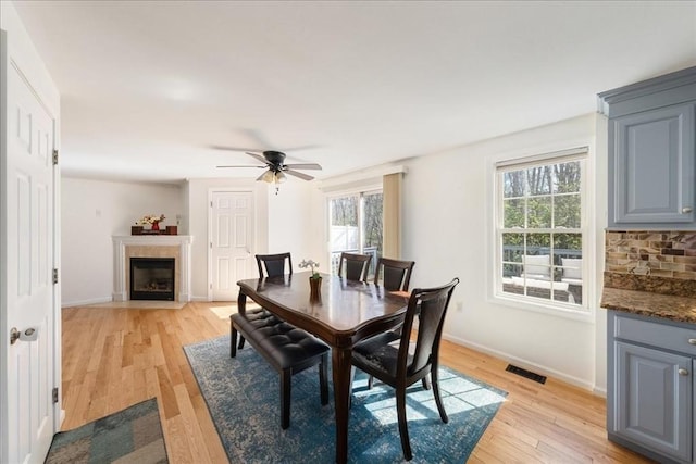 dining area with a wealth of natural light, light wood-type flooring, ceiling fan, and visible vents
