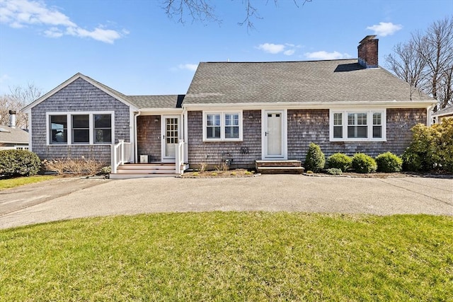 view of front of house with a chimney, roof with shingles, and a front lawn