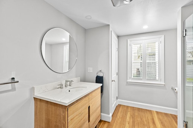 bathroom with recessed lighting, baseboards, wood finished floors, and vanity