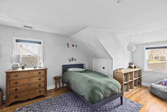 bedroom with visible vents, wood finished floors, vaulted ceiling, and multiple windows