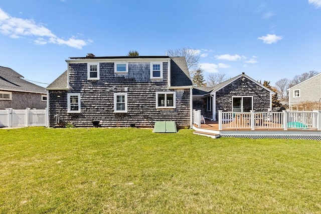 rear view of house with a yard, a deck, and fence