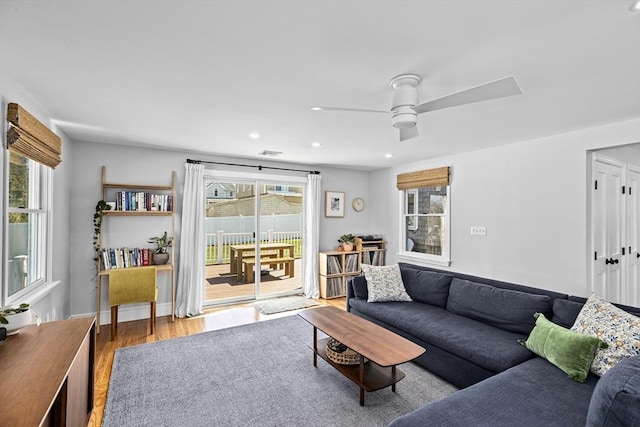 living area with a ceiling fan, visible vents, wood finished floors, baseboards, and recessed lighting