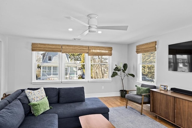 living room featuring visible vents, ceiling fan, wood finished floors, and a wealth of natural light