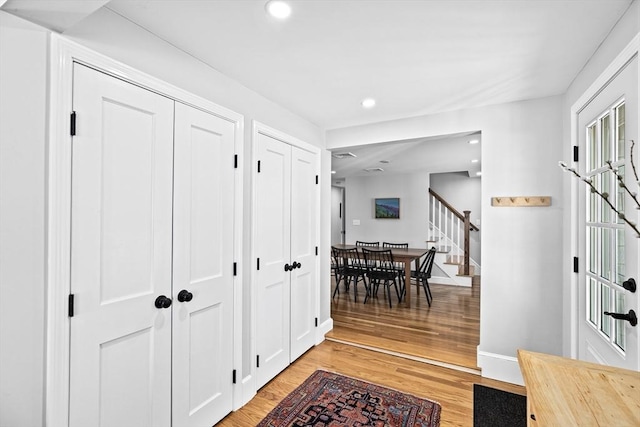 hallway with baseboards, recessed lighting, light wood finished floors, and stairs