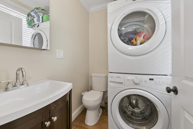 washroom featuring dark wood-type flooring, ornamental molding, stacked washer / dryer, and sink