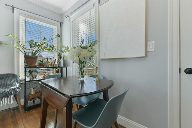 dining space with ornamental molding and dark hardwood / wood-style floors