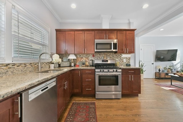 kitchen featuring sink, light hardwood / wood-style flooring, appliances with stainless steel finishes, light stone counters, and ornamental molding