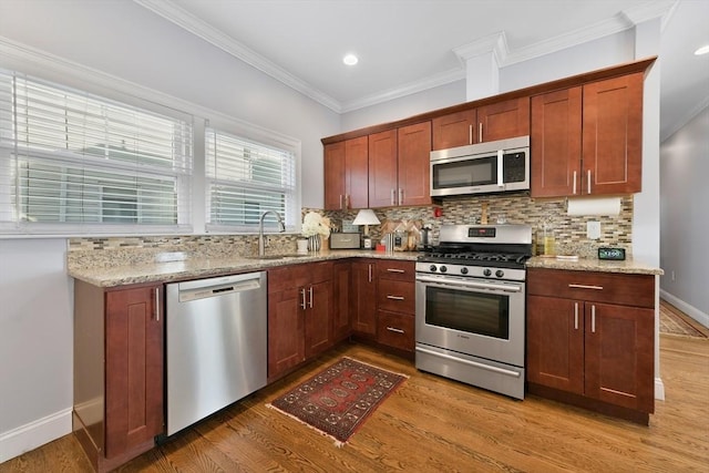 kitchen featuring appliances with stainless steel finishes, tasteful backsplash, sink, light stone counters, and crown molding