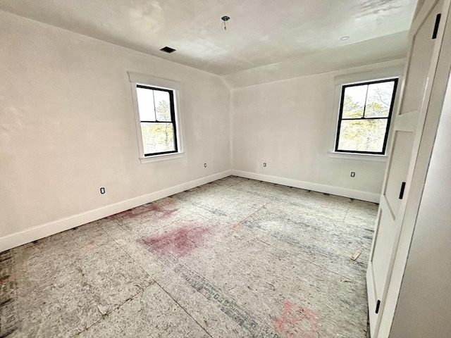 spare room with a wealth of natural light and baseboards