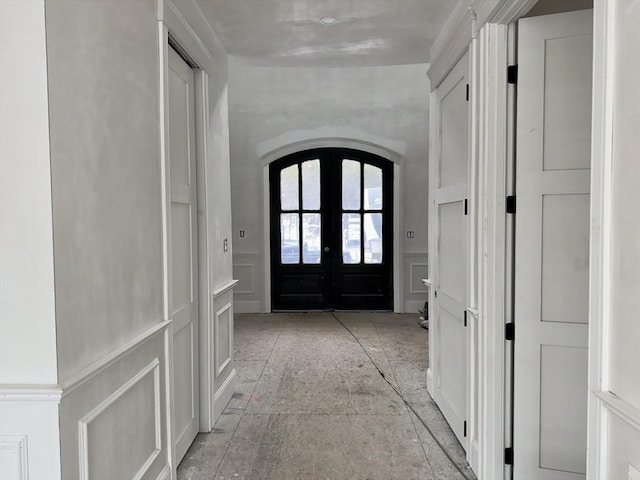 interior space with wainscoting, arched walkways, a decorative wall, and french doors