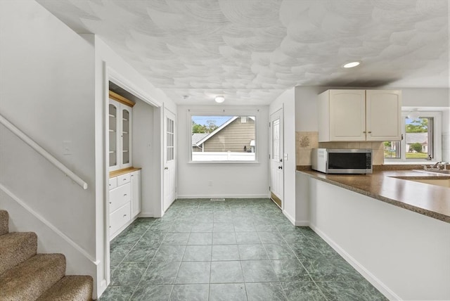 76 Choctaw Dr, Wareham, MA 02532 - kitchen featuring stainless steel microwave, white cabinetry, baseboards, decorative backsplash, and dark countertops